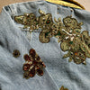 close-up of gold floral appliqué embroidery on the back of the denim jacket