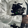 Close-up of a white denim jacket with black lace appliqué and colorful stones.